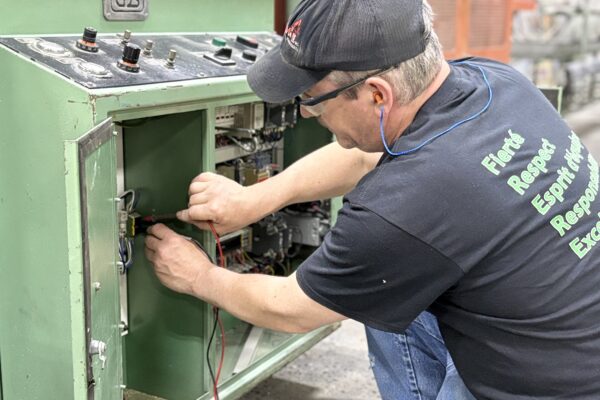 Électromécanicien effectuant un diagnostic électrique sur un équipement industriel.